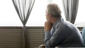 Old man sitting down looking out the window wondering if he has DVT in Minneapolis, MN